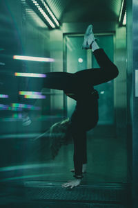 Side view of woman doing handstand at doorway