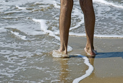 Low section of man standing on beach