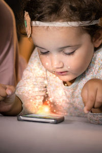 Girl with mother using phone while relaxing on bed at home