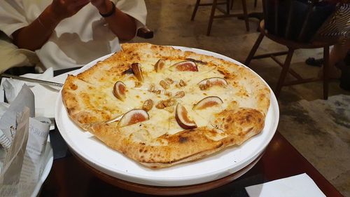 Delicious italian handmade pizza, honey with fresh fig, walnut, cheese, closeup,holding pizza, table