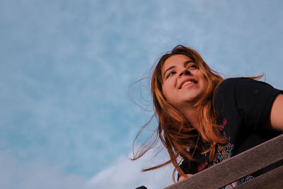 Portrait of smiling young woman against sky
