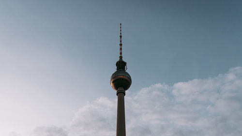 Low angle view of communications tower against cloudy sky