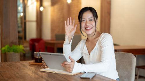 Young woman using laptop while sitting on bed at home