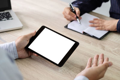 Midsection of man using mobile phone on table