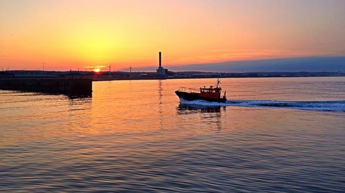 Boat sailing in sea against sky during sunset