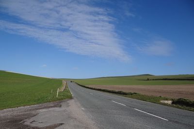 Road amidst field against sky