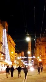 Woman standing on illuminated city street at night