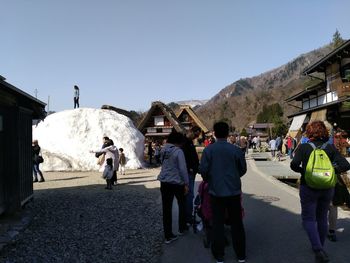 People walking on street in city against clear sky