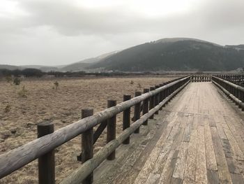 Footbridge over landscape against sky