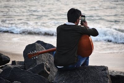 Rear view of man photographing on beach