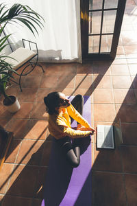 Young caucasian brunette woman practicing yoga at home sitting in lotus pose. vertical format.