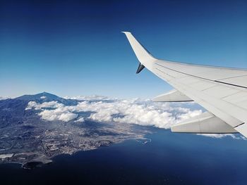 Airplane flying over snowcapped mountains against clear blue sky