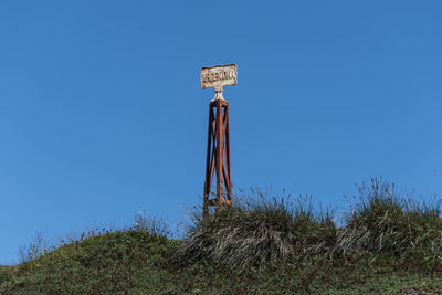 Low angle view of cross on field against clear blue sky