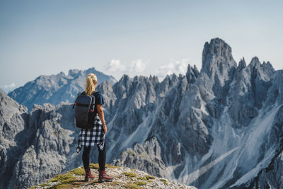 Rear view of man standing on mountain against sky