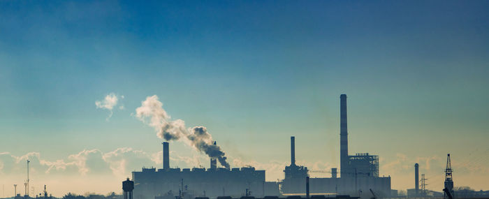 Smoke emitting from factory against sky