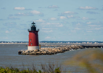 Lighthouse by sea against sky