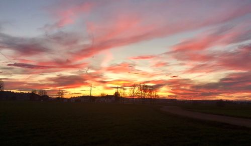 Scenic view of dramatic sky over silhouette landscape during sunset