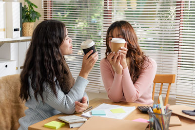 Young woman using mobile phone while sitting at office