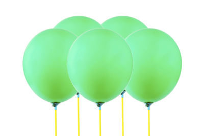 Close-up of green helium balloons against white background