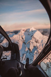 Low section of man in helicopter against snowcapped mountains 