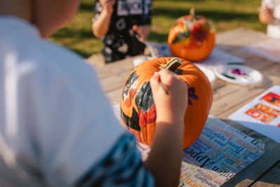 Close-up of child hands while painting pumpkin for halloween