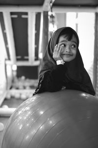 Thoughtful girl smiling with fitness ball in gym