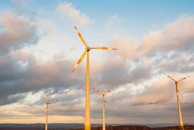 Low angle view of wind turbine against sky during sunset