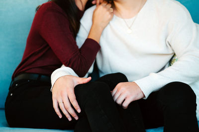 Crop view of anonymous couple tenderly hugging while sitting on soft sofa in cozy living room