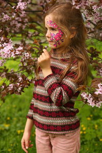 Spring portrait of a six year old girl standing under the blooming pink cherry tree