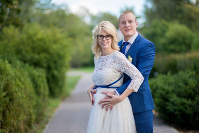 Portrait of newlywed couple standing on footpath at park