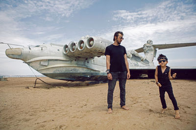 Family a boy and his father in rocker clothes stand ekranoplan plane by the sea in dagestan