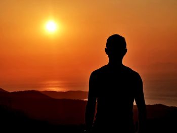 Silhouette man standing against orange sky during sunset