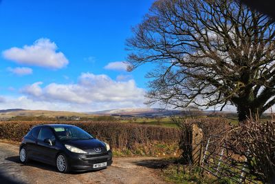 Car on landscape against blue sky