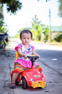 Cute girl looking away while sitting on road