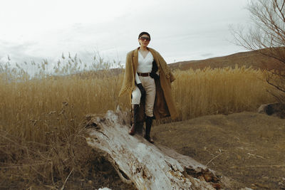 Portrait of young woman standing on field against sky