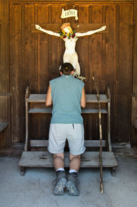 Full length rear view of boy sitting on wood