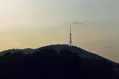 Silhouette of communications tower against sky during sunset