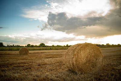 Hay bales on field against sky