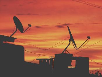 Low angle view of silhouette cranes against sky during sunset