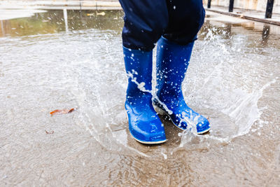 Low section of person splashing puddle water during rainy season