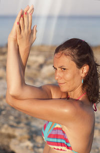 Young woman with sunglasses on beach against sky