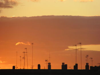 Silhouette electricity pylon against sky during sunset
