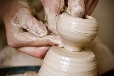 A man with his hands dub wall jug, which he sculpts out of clay on a circle. create clay vessel.