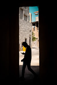 Side view of silhouette woman standing against building