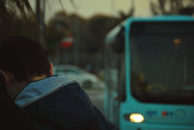 Rear view of man by bus on street at dusk