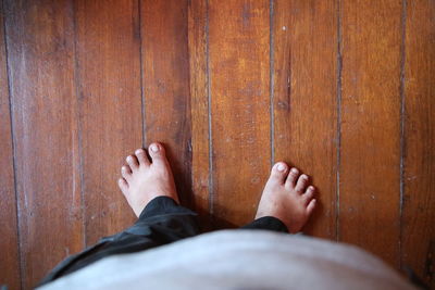 Low section of man standing on wooden floor