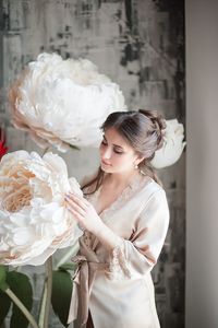 Woman looking at flower decoration against wall