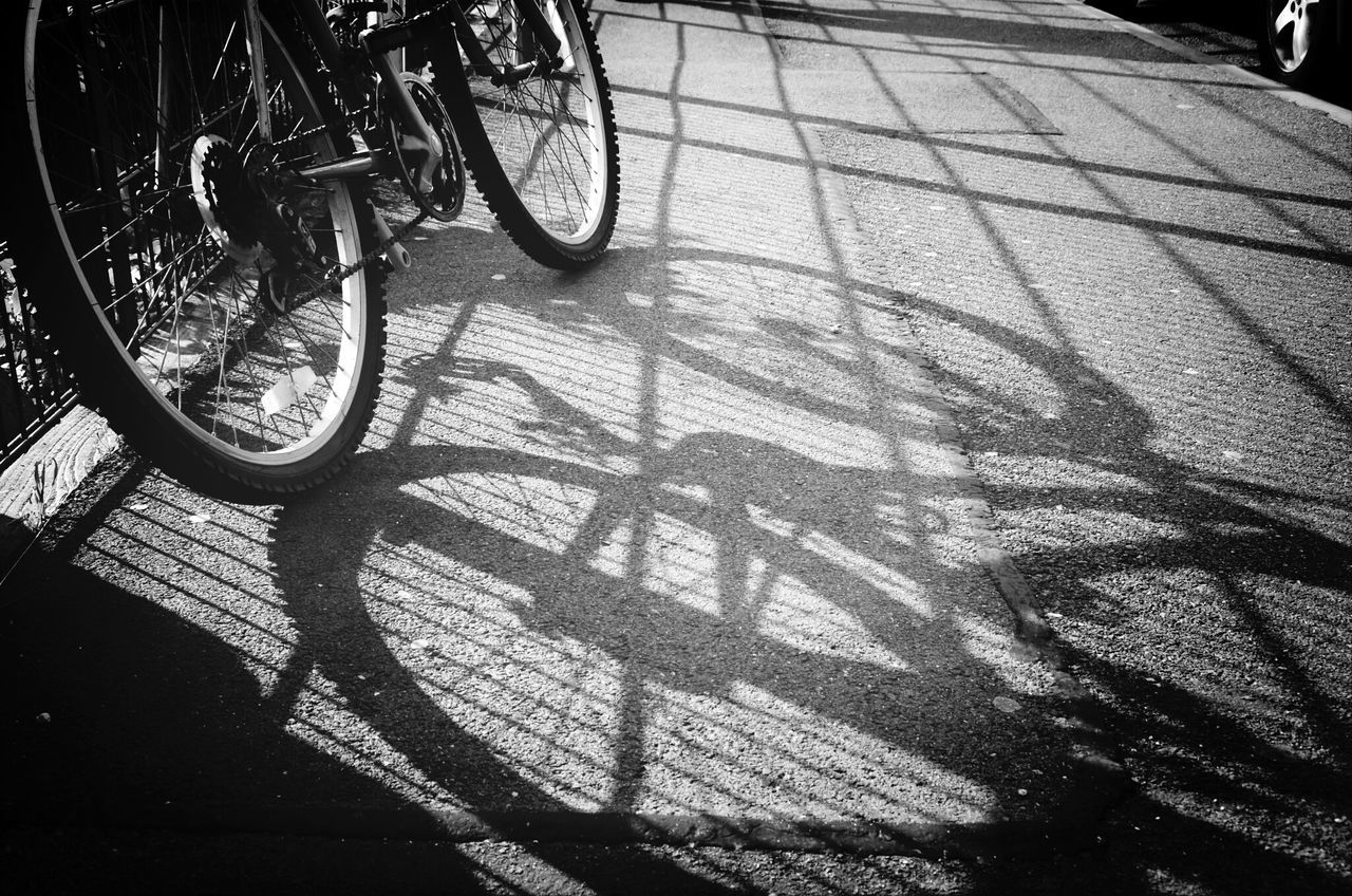 bicycle, transportation, land vehicle, mode of transport, shadow, street, parking, stationary, parked, sunlight, high angle view, road, day, travel, wheel, outdoors, cycling, tree, riding, no people