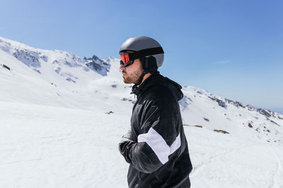 Man standing on snow covered mountain against sky