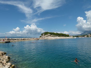 People enjoying summer in sea against sky